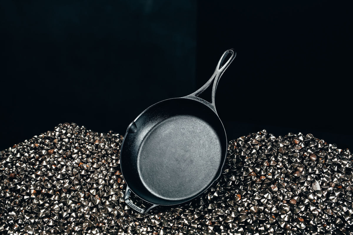 Skillet laying in pile of ground iron.