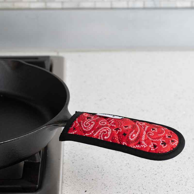 Handle holder being used on skillet on stove.