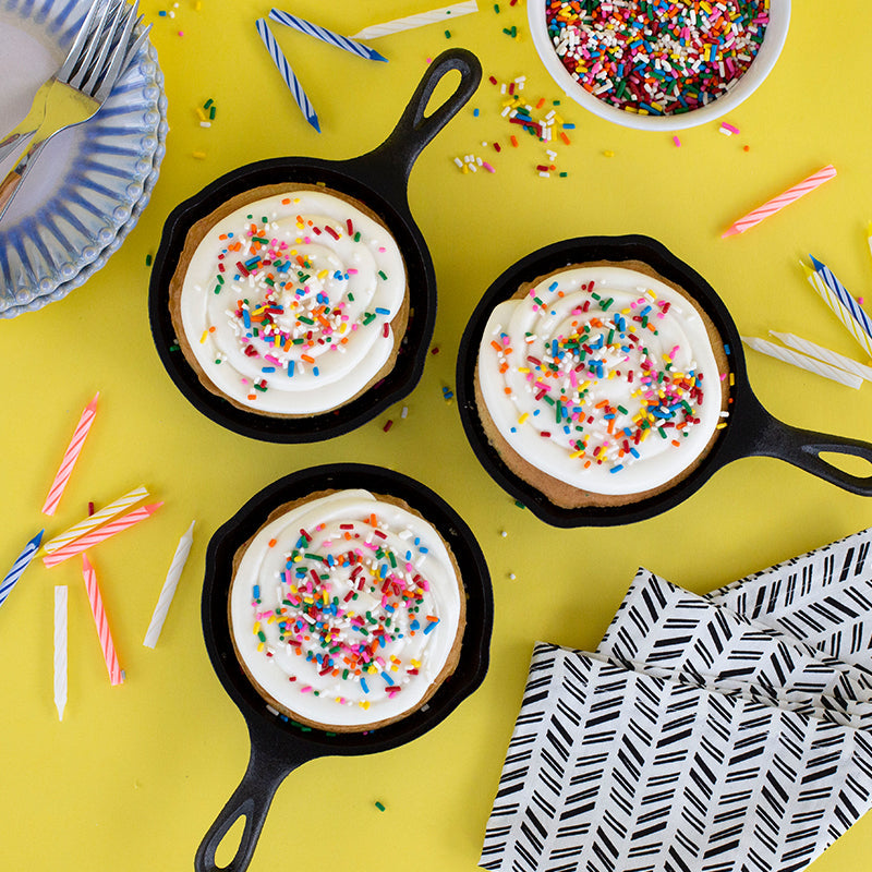 3 frosted skillet cookie cakes on a birthday party themed background.