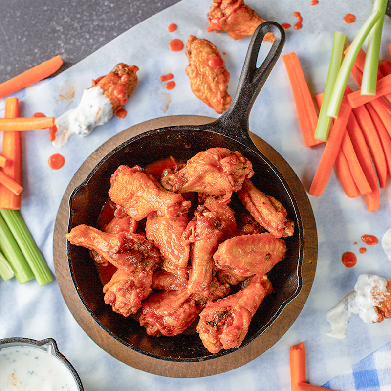 Buffalo chicken wings served in skillet with underliner.
