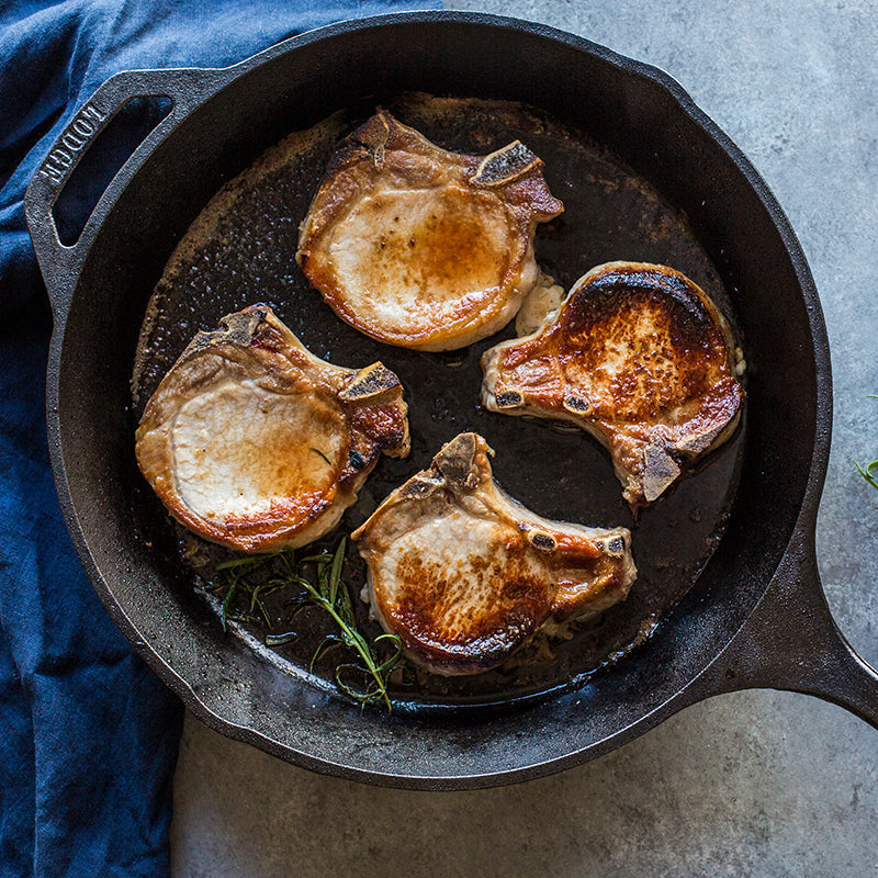 Seared pork chops in skillet.