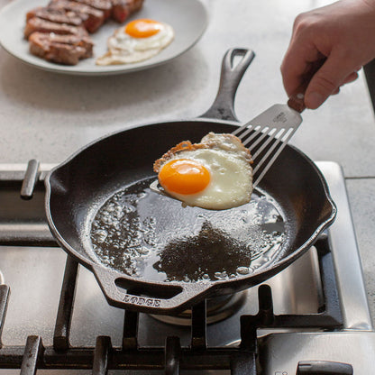 Someone flipping egg in cast iron skillet.