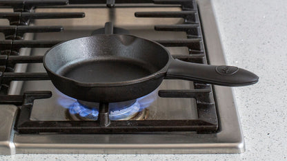 Silicone handle holder on skillet cooking on stove.