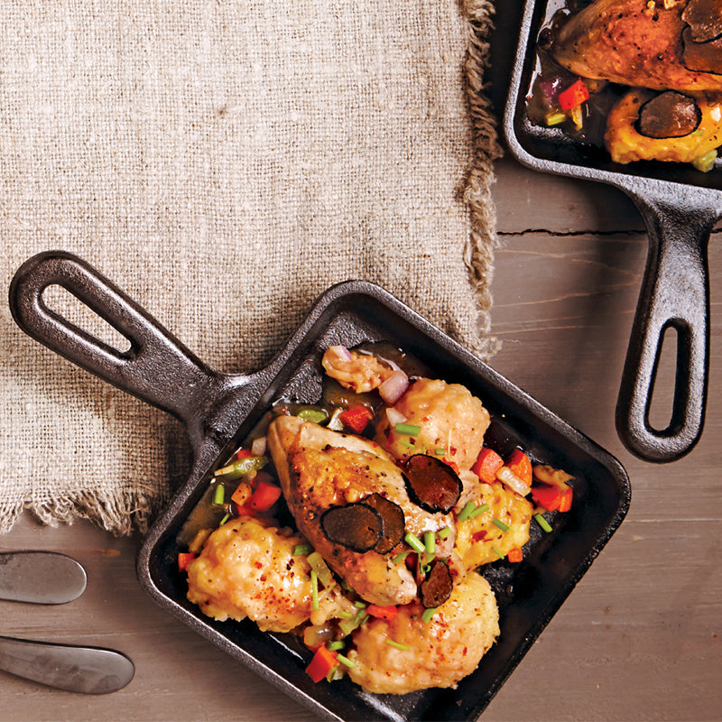 Cooked chicken with veggies served on table with skillet.