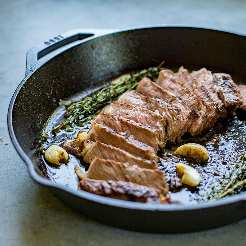 Freshly made steak served in pan with garlic and rosemary.