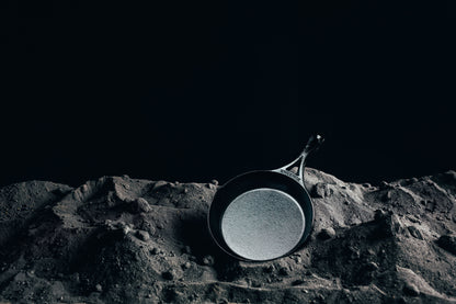 Skillet laying in pile of ground iron.